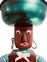 Detail of orange and green legs on the brown bottle-cap figure with carved nose and mouth by the Oshkosh Master - vernacular art