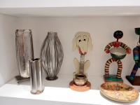 Middle shelf left  from Chicago We Own It: stainless steel Stanley Szwarc vases,  bottle-cap figures