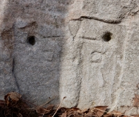 Cryptic face next to triangle-bodied figure. Chicago lakefront stone carvings at Fullerton. 2019