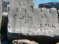 Autograph rock: E.Mch, VB, BF, E, JMK, BC, Mitch. Chicago lakefront stone carvings, south of La Rabida Hospital, 65th Street and the Lake. 2023