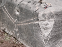 Joel Cardenas completed this face during Promontory Point festivities in May 2023, next to his figure with sun from October 2022. Level 5, vertical. Chicago lakefront stone carvings, Promontory Point. 2023